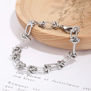 Silver rectangle link bracelet with knot design on a wooden display for fashion jewelry