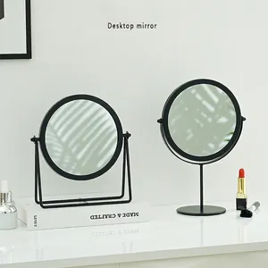 Specchio per trucco rotondo nero minimalista con cornice in metallo su tavolo bianco