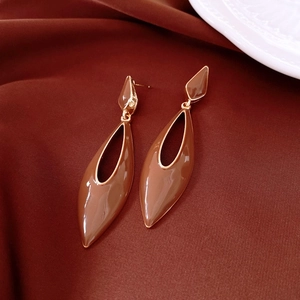 Détail de boucles d'oreilles gouttes en émail marron avec bordure en métal doré chic