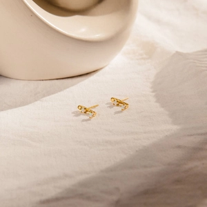 Close-up of elegant gold-plated mini studs featuring shimmering white opal stones