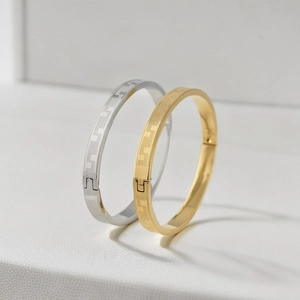 Detail of gold and silver titanium steel bracelets with geometric T-pattern and clasp
