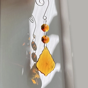 Detail of amber crystal suncatcher with teardrop prism casting light patterns
