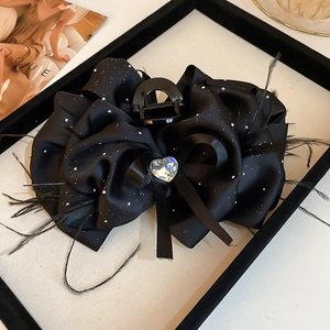 Détail de pince à cheveux nœud en satin noir avec strass cœur et plumes élégantes