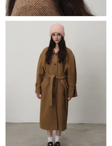 Detailed full-length shot of a brown wool coat with a waist belt and pink knit beanie
