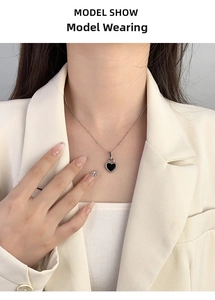 Close-up of S925 silver necklace with black heart pendant on a model with beige blazer