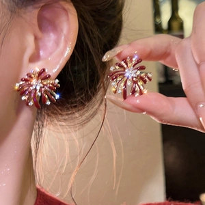Detail of red firework earrings with gold frame and sparkling zircons for women