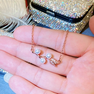 Close-up of rose gold necklace with white pearls and sparkling leaf detail for women