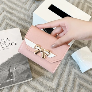 Detailed macro view of pink leather texture and golden bow-knot metal clasp on a wallet