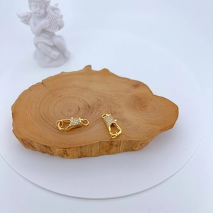 Macro view of gold plated lobster clasps with micro-pave zircons on a wooden base