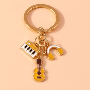 Detailed view of music-themed keychain featuring enamel piano, headphone and guitar charms