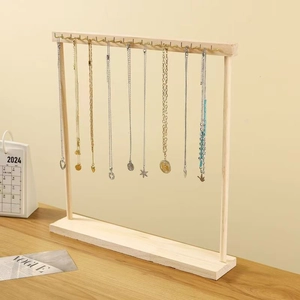 Detail of wooden T-bar jewelry display stand with metal hooks holding gold and silver necklaces