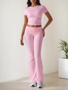 Detail of pink knitted yoga set showing crop top and flared high-waisted pants