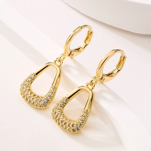 Close-up of geometric triangular gold earrings with sparkling pave zircon on white stand