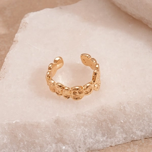 Macro shot of gold textured ring with abstract faces on white crystal stone