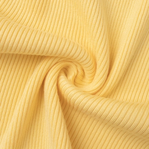 Gros plan du tissu en maille côtelée jaune vif montrant l'élasticité et le drapé doux