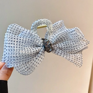 Detail showing polka dot mesh fabric bow hair claw clip with transparent black and white texture