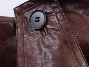 Detailed close-up of brown faux leather texture with a black four-hole button and stitching