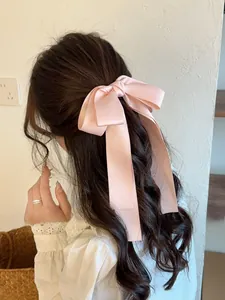 Détail d'un nœud papillon en satin rose style balletcore avec de longs rubans