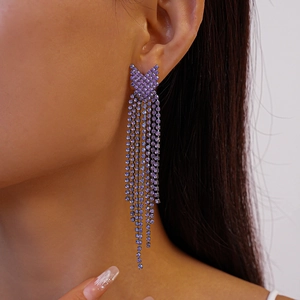 Elegant purple rhinestone tassel earrings with a geometric V-shape design on a model