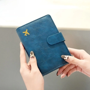 Blue leather RFID blocking passport holder with gold airplane accent and snap closure
