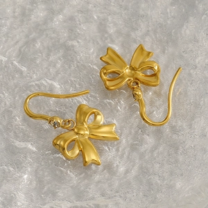Vue macro de boucles d'oreilles nœuds dorées avec finition mate et pierre scintillante