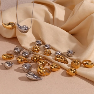 Macro shot of 18K gold plated hollow teardrop earrings on elegant champagne silk fabric