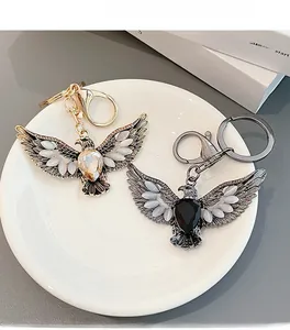 Detailed view of gold and gunmetal eagle keychains with opal wings and teardrop stones