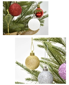 Close-up of glitter and glossy Christmas ball ornaments hanging on green pine branches