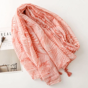 Flat lay of pink and white scarf with geometric stripes and decorative tassels