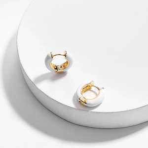 Detail of round gold earrings with white enamel finish and secure clasp closure