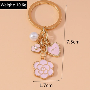 Detail of camellia keychain with pink enamel heart, white pearl, and gold polished hardware