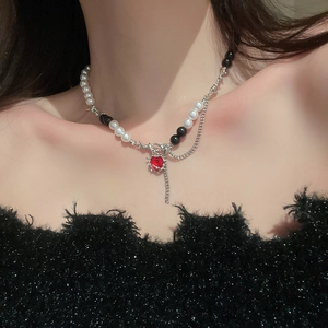 Cool gothic style necklace with red heart pendant, white pearls and black beads on a model
