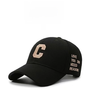 Close-up of the beige C letter embroidery and text on a black curved brim baseball cap