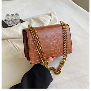 Close-up of brown crocodile pattern faux leather with gold metal chain straps details