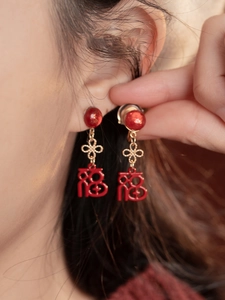Gros plan détaillé des boucles d'oreilles rouges Fu avec nœuds Ruyi dorés