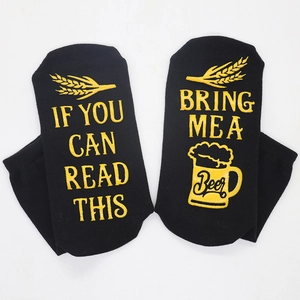 Detail of black cotton socks with yellow embroidery text IF YOU CAN READ THIS BRING ME A Beer