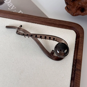 Detail of a translucent black tortoiseshell hair claw with a glossy spherical ornament