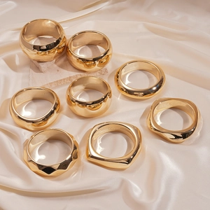 Set of eight gold geometric acrylic rings with polished mirror finish on silk background