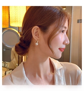Detail of luxury pearl drop earring with gold diamond-set base worn by a model