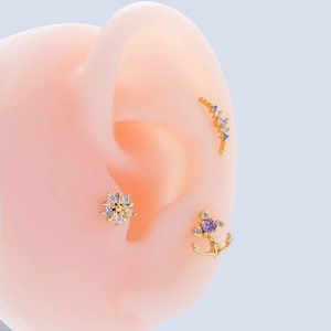 Detailed view of gold stainless steel cartilage studs with zircon floral and moon designs