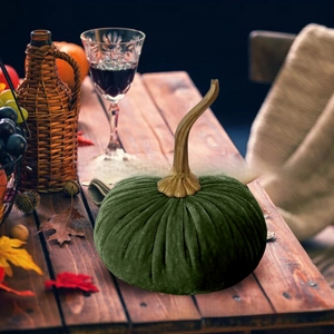 Detail of dark green velvet decorative pumpkin with a long curved golden stem for holidays