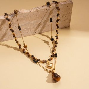 Détail du collier de perles en œil de tigre plaqué or 18k avec pendentifs cœur et gourde