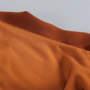 Detailed close-up showing fine stitching and crepe texture of the orange evening dress