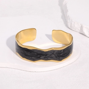 Vue détaillée du bracelet jonc doré aux bords ondulés avec incrustation de marbre noir