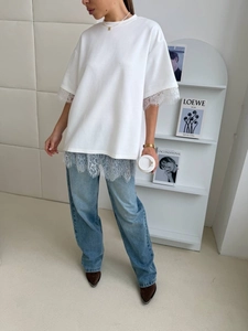 Detail of white loose T-shirt with delicate lace patchwork hem and casual summer design