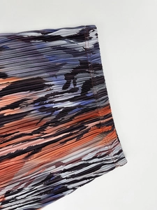 Macro view of high-density pleated fabric with colorful abstract flowing print detail