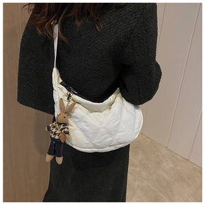 Detailed view of white quilted crescent bag with cute rabbit charm and zipper closure