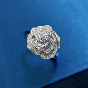 Macro shot of silver camellia ring with micro-set sparkling crystals on blue background