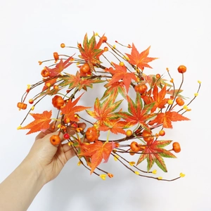 Close-up of fall wreath featuring orange pumpkins, maple leaves, and yellow berries