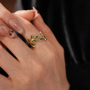 Detailed close-up of a vintage golden leaf ring with green enamel on a dark background